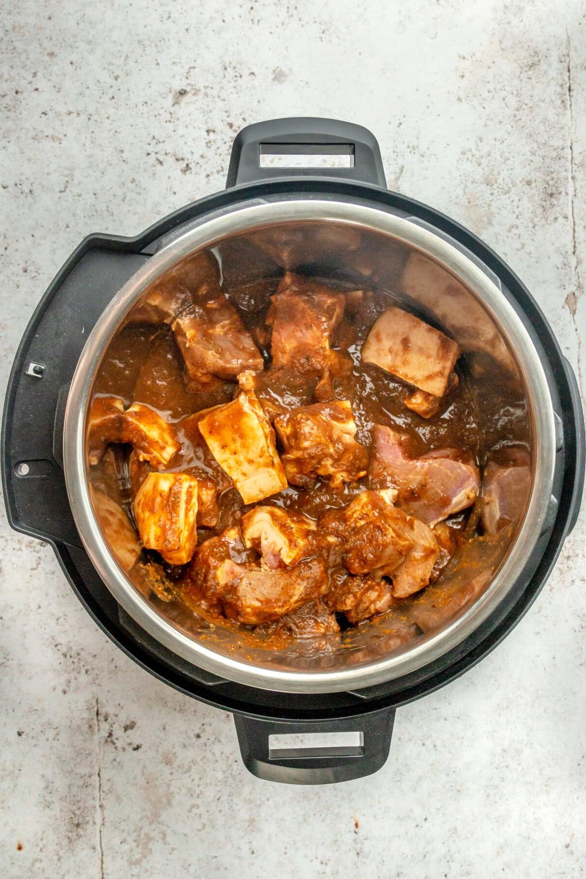 Stücke von mariniertem Schweineschulterfleisch im Slow Cooker, bereit zum Garen.