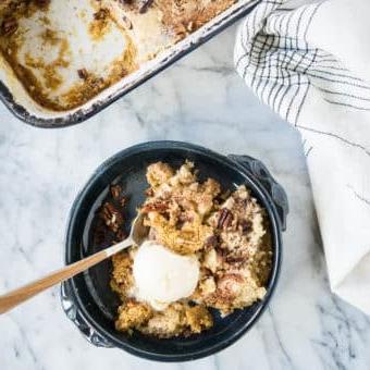 Dunkelblaue Schüssel mit Kürbis-Dump-Cake und einer Kugel Eiscreme darauf.