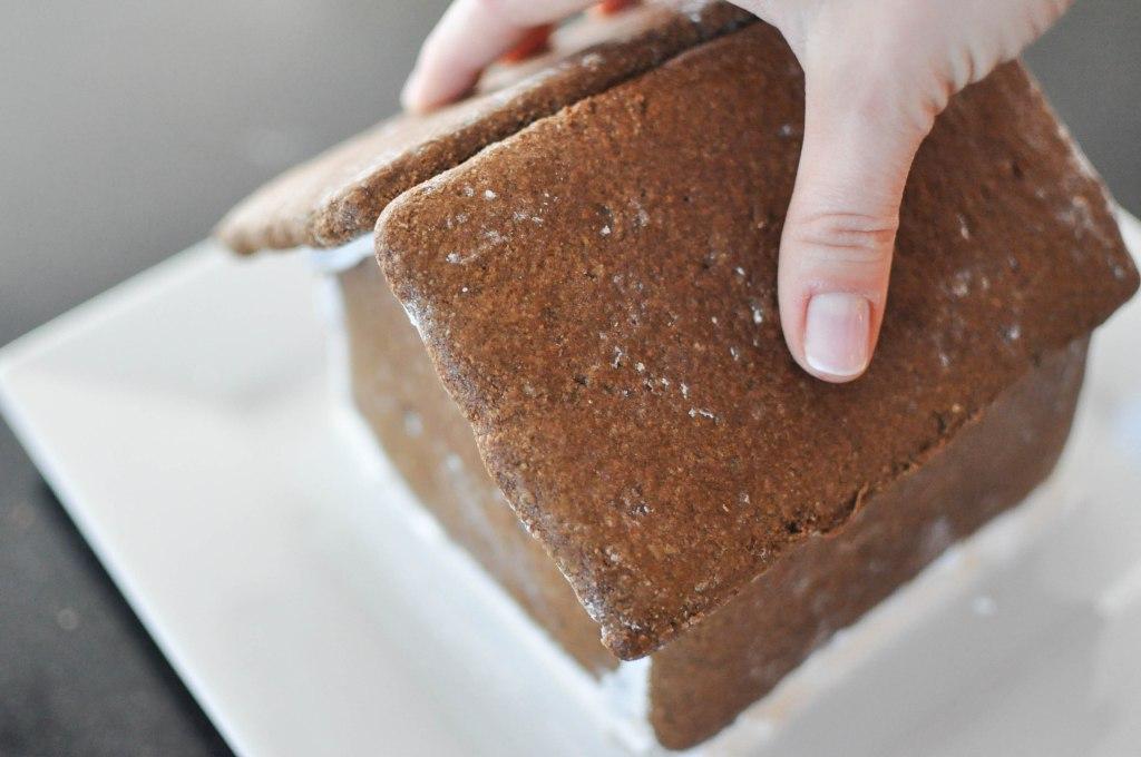 Nähte des Lebkuchenhauses mit Glasur verzieren