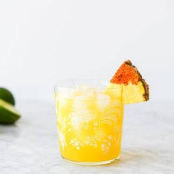 Ein Margarita-Glas mit einem Ananas Margarita auf Eis, garniert mit einem in Chili-Salz getauchten Ananas-Keil.