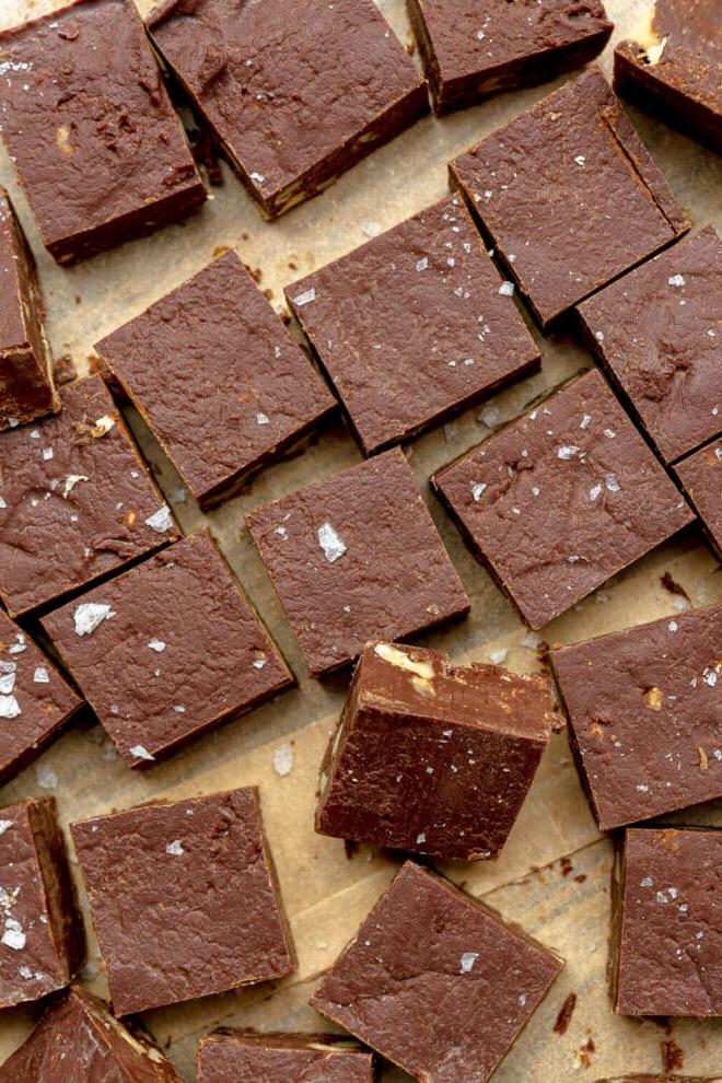 Hausgemachtes Schokoladen-Walnuss-Fudge 4 Kleine Quadrate aus Schokoladenfudge auf einem braunen Stück Backpapier.